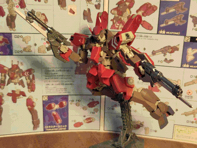 A photo of the high-grade Schwalbe Custom model kit, posed in the air on a stand. It is a red and brown mech with sharp, angular knight-like armor panels and a skeletal frame. The head has two narrow slits for optical sensors, one above the other, and it has thrusters embedded in the knees, shoulders, and on 'arms' on the back of the mobile suit. The left shoulder has two white chevron markings on it, and it has a sharp antenna on each side of its head, which have white tips. It is wielding two revolver-like guns, one in each hand, and each one has a long blade attached underneath and extending beyond the barrel. The instruction manual for the kit is visible in the background.