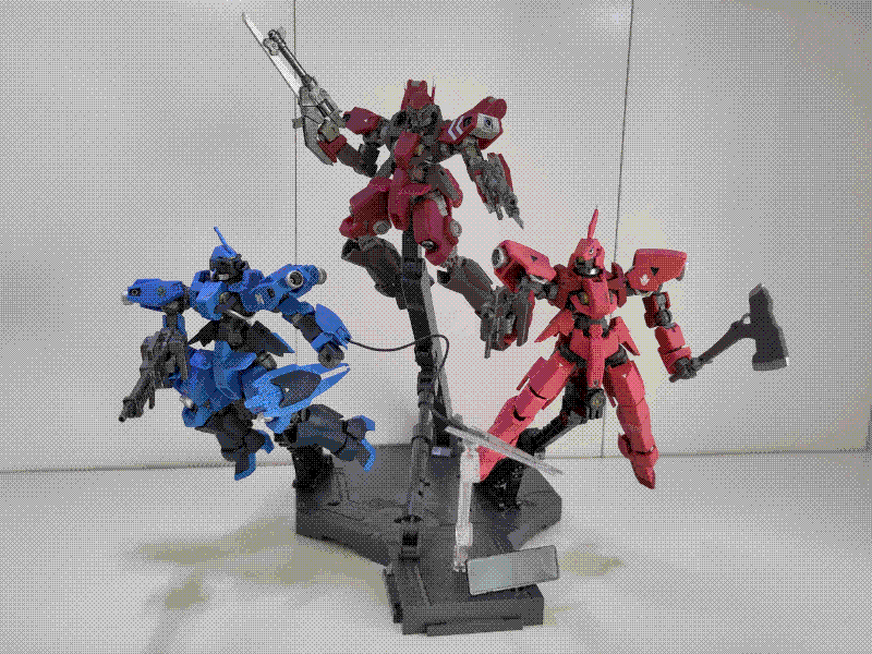 A photo of the McGillis' Schawlbe Graze, the Schawlbe Custom, and Ryusei-Go models all posed in the air with a large stand. The photo is head-on, with McGillis' Schawlbe facing to the right with its blade extended on a wire, the Schwalbe Custom at the top and brandishing both guns, and the Ryusei-Go facing to the left while aiming its gun and holding its axe.