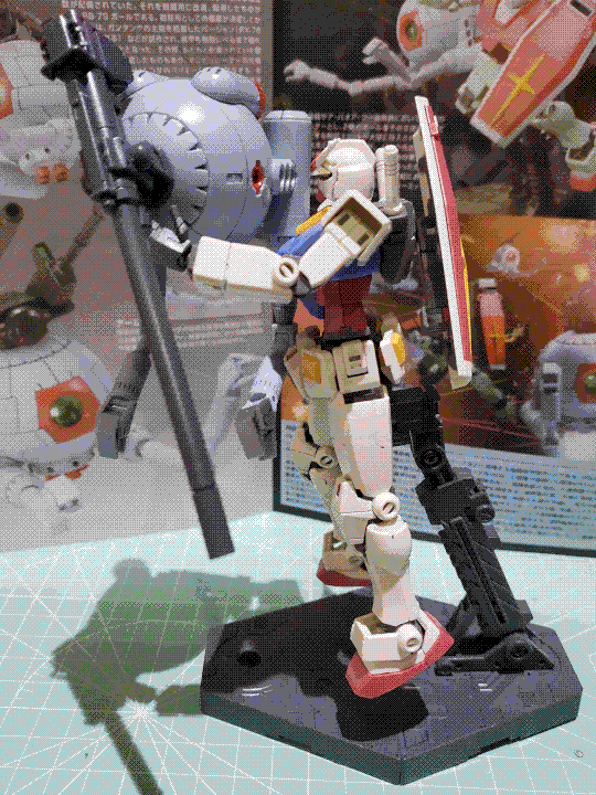 A photo of the RB-79 Ball model kit being carried in the arms of the the RX-78-2 high-grade 'Beyond Global' kit.