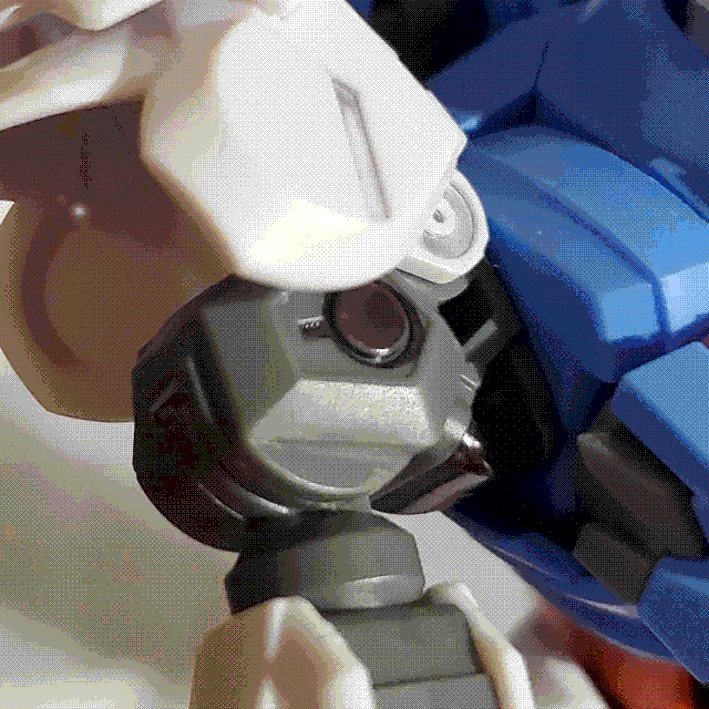 A zoomed in photo on the shoulder of the Gundam Aerial. The white shoulder armor has been flipped up, exposing a grey frame underneath with some metallic gunmetal detailing.